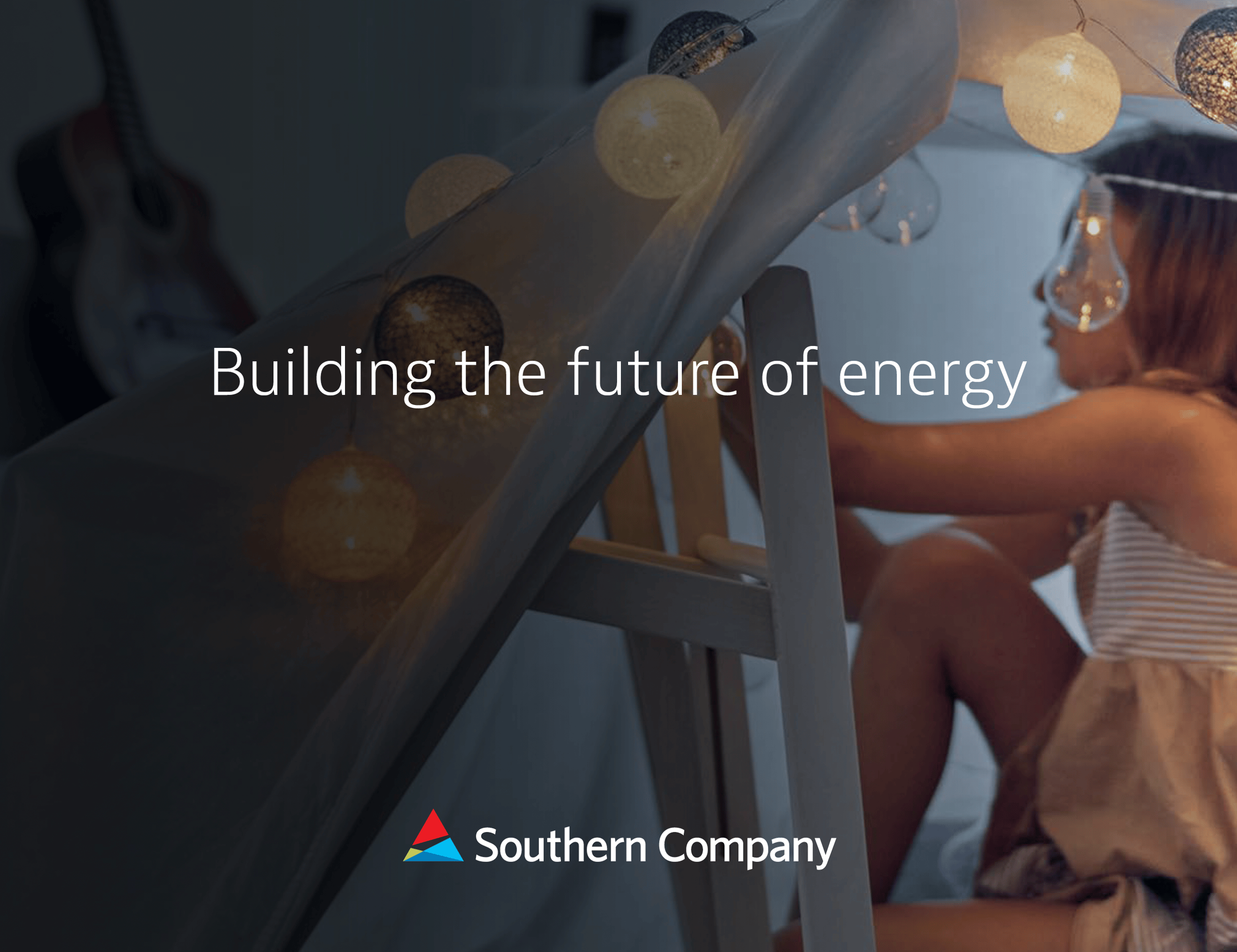 Child standing behind a ladder-like structure beneath warm string lights, with energy-themed text.